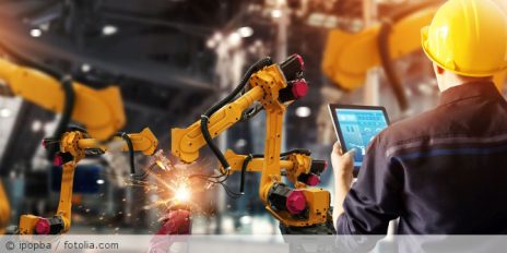 Ein Mann der mit einen Tablet einen Roboter steuert.