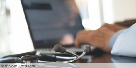 Arzt tippt etwas in seinen Laptop.