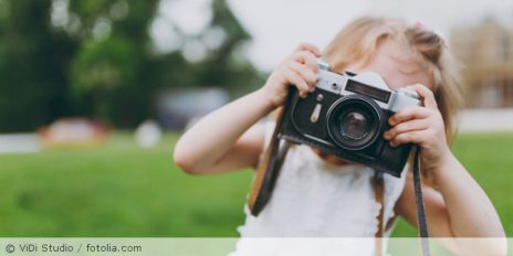 Kind macht Foto mit einer Kamera.