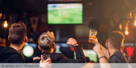 Menschen schauen in einer Kneipe Fußball.