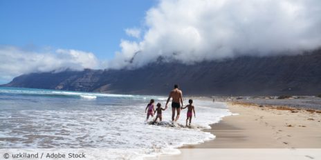 Vater mit drei Kindern am Meer.