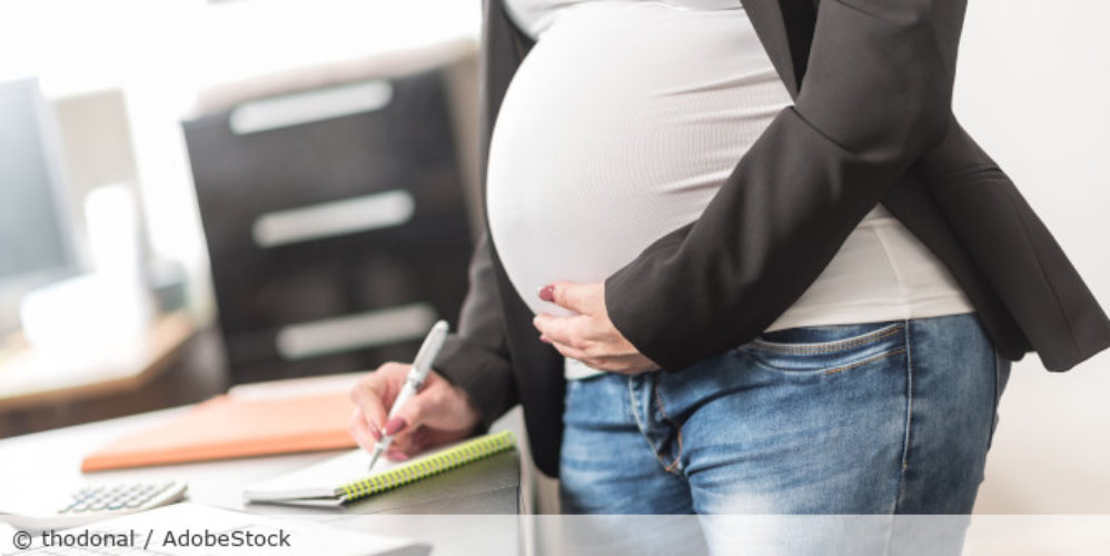 Schwangere Frau schreibt etwas in ein Notizbuch.