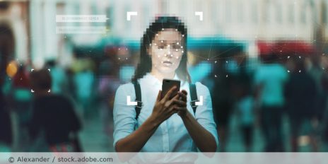Frau läuft durch Innenstadt mit Handy in der Hand. Um ihr Gesicht ist eine Gesichtserkennung.