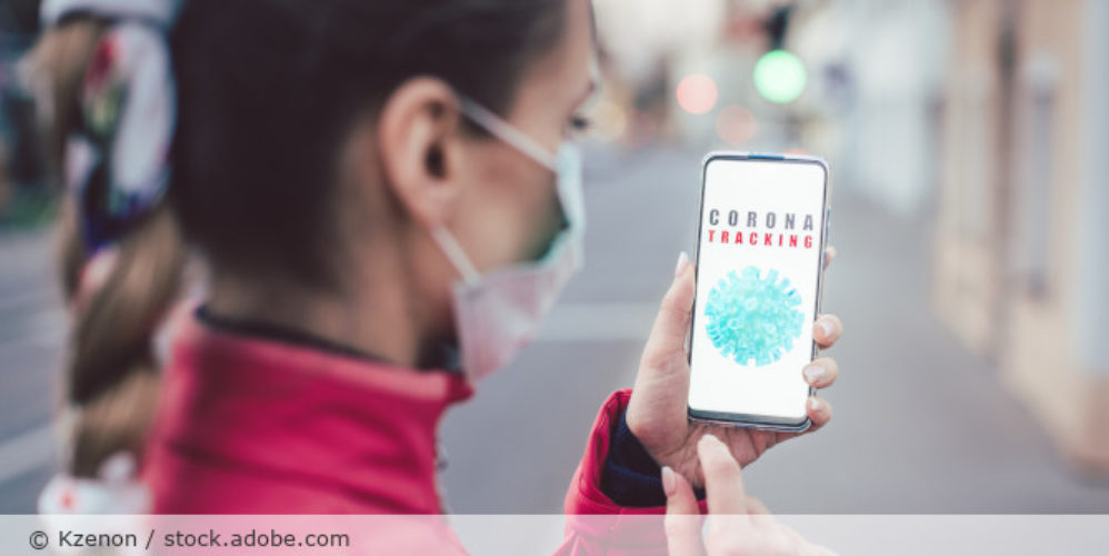 Frau mit Maske und Corona Tracking App.