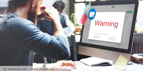 Mann am Computer mit einer Mail-Warnung.