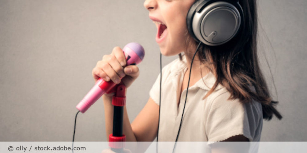 Kind singt in ein Mikrofon.
