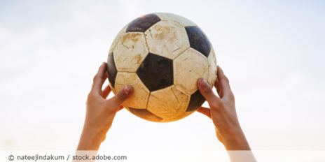 Person hält einen Fußball hoch.