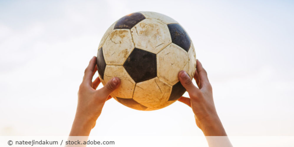 Person hält einen Fußball hoch.