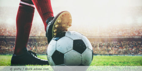 Person hält den Fußball mit seinen Fuß fest.