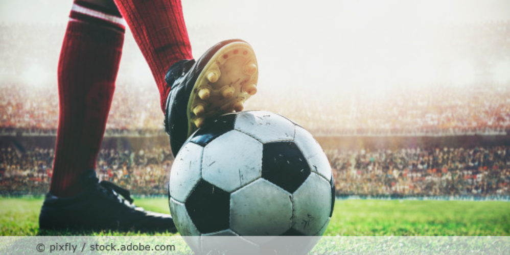 Person hält den Fußball mit seinen Fuß fest.