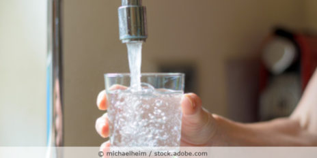 Frau füllt ihr Wasser mit den Wasserhahnauf.