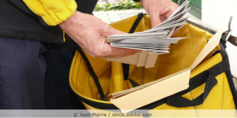Postbote nimmt mehrere Briefe aus seiner Posttasche