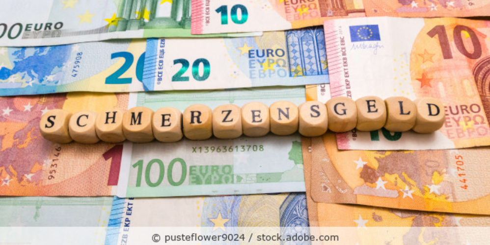 Würfel mit der Aufschrift "SCHMERZENSGELD". Darunter mehrere Geldscheine.