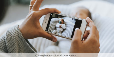 Frau macht ein Foto eines Neugeborenen mit dem Smartphone