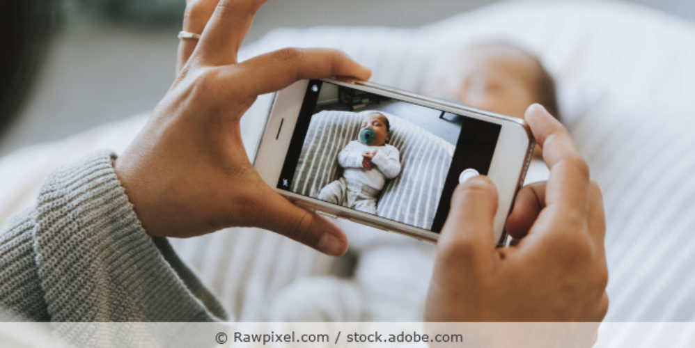 Frau macht ein Foto eines Neugeborenen mit dem Smartphone