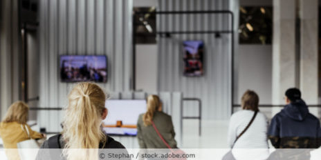 Menschen sitzen im Museum und schauen auf Monitore