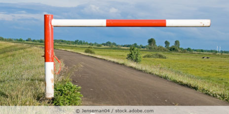 Eine einfache rot-weiße Schranke auf einem Deich.