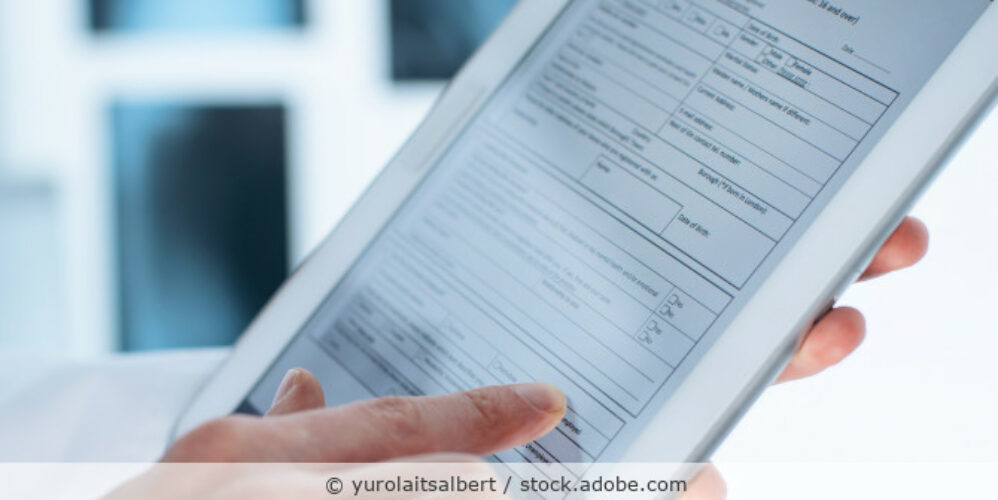 Mann hält ein Tablet in der Hand, auf dem ein Formular zu sehen ist.