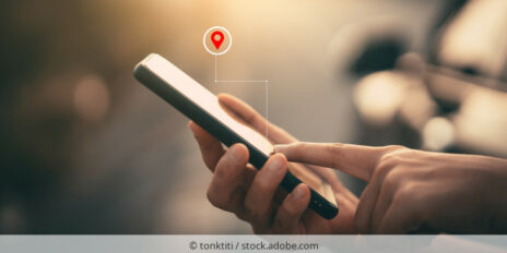 Person hält ein Smartphone in der Hand über dem das Symbol für den Standort eingeblendet ist.