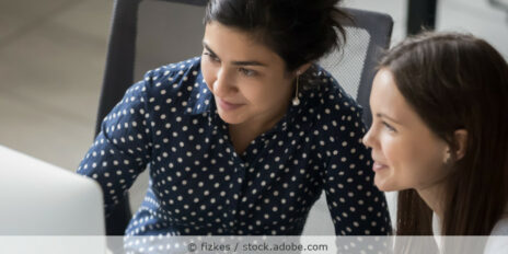 Zwei Frauen schauen gemeinsam im Büro am Schreibtisch auf einen Bildschirm.