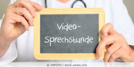 Arzt hält ein Schild mit der Aufschrift Videosprechstunde.