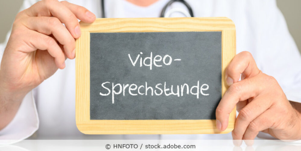 Arzt hält ein Schild mit der Aufschrift Videosprechstunde.