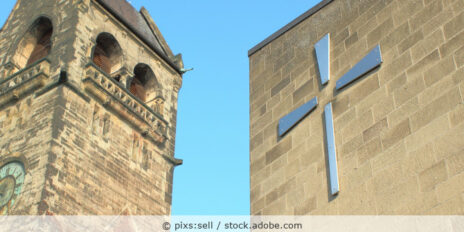 Evangelische Kirche von außen mit Nebengebäude und Kreuz.