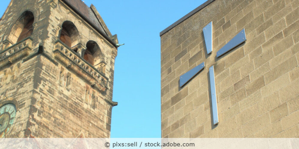 Evangelische Kirche von außen mit Nebengebäude und Kreuz.