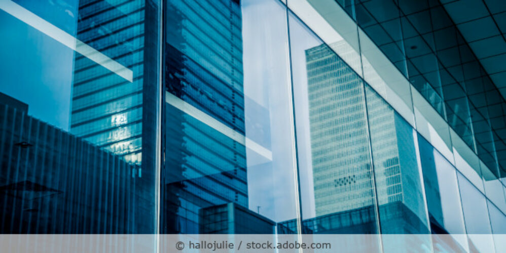 Fassade eines Bürogebäudes als Reflektion in den Fenstern eines anderen Gebäudes.