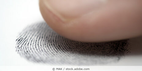 Finger und ein Fingerabdruck auf Papier in der Nahaufnahme.