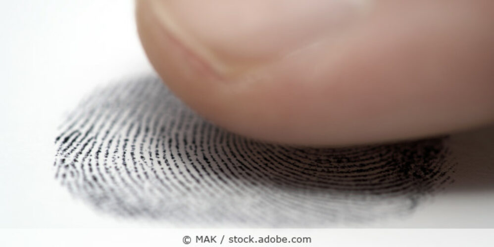 Finger und ein Fingerabdruck auf Papier in der Nahaufnahme.