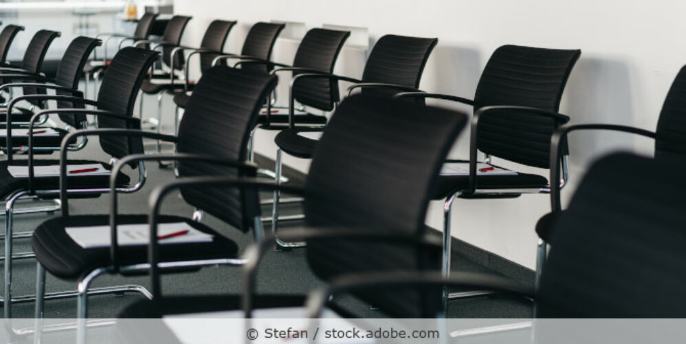 Schwanze Bürostühle stehen in Reihen in einem Konferenzraum.