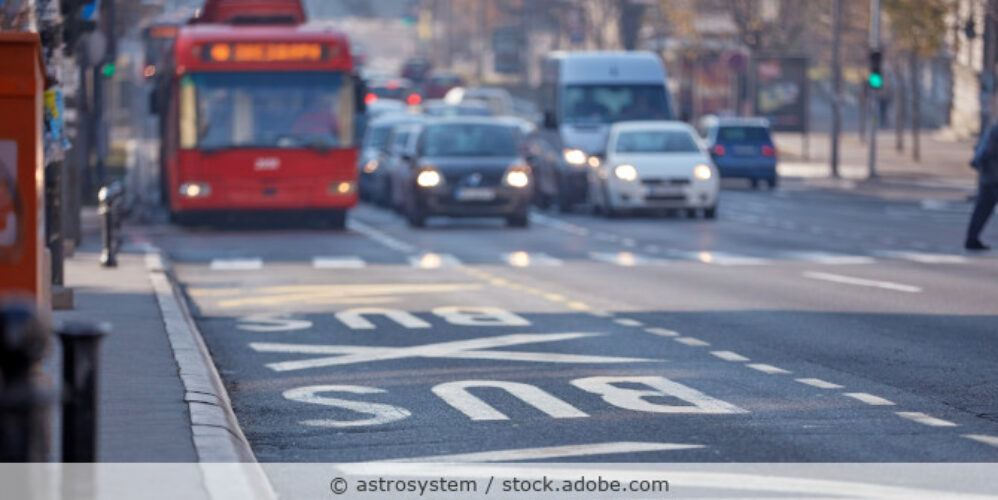 Mehrspurige Straße in der Stadt mit Bus, Autos und einer Busspur.