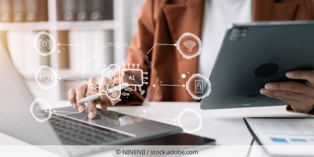 Person nutzt Künstliche Intelligenz am Schreibtisch mit Laptop und Tablet.