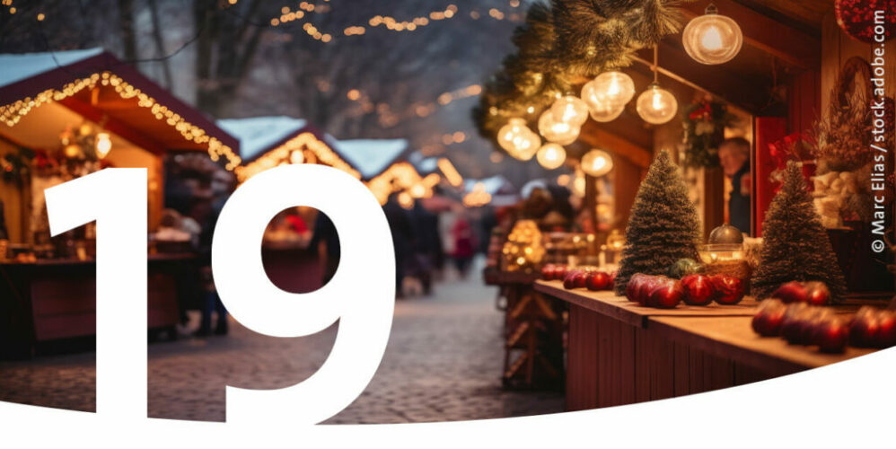 Mit Lichtern dekorierte Hütten auf einem Weihnachtsmarkt als Bild für den 19. Dezember im Adventskalender.
