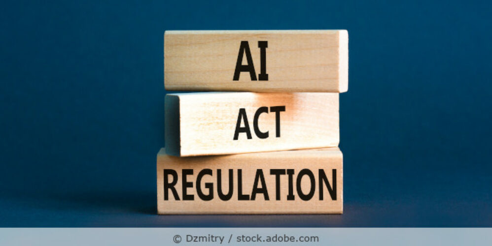 „AI Act Regulation“ steht auf drei übereinanderstehenden Holzklötzen vor einem dunkelblauen Hintergrund.