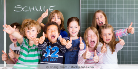 Schüler bei der Einschulung sitzen vor der Tafel und freuen sich.