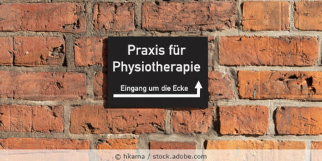 Schild einer Praxis für Physiotherapie hängt an einer Backsteinmauer.