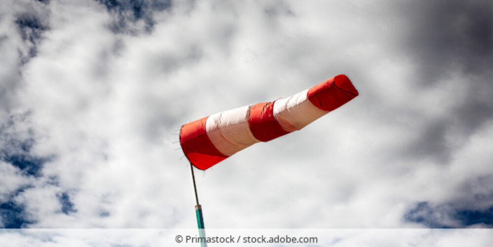 Windfahne bei stärkerem Wind vor bewölktem Himmel.