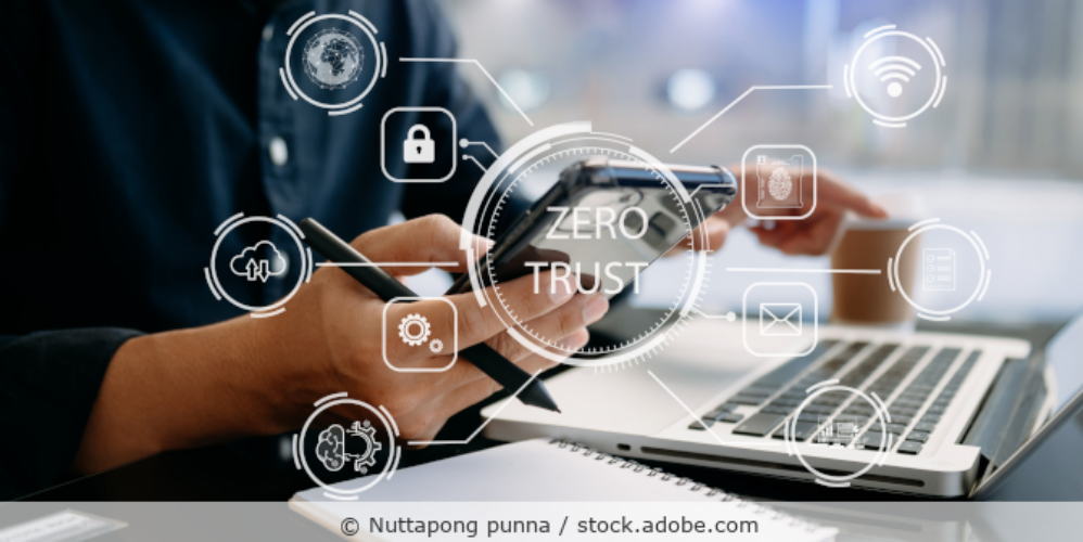 Zero Trust Sicherheitskonzept – Person mit Computer und Tablette mit Zero Trust Symbol auf dem virtuellen Bildschirm in modernem Büro.