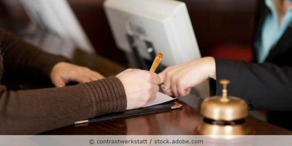 Eine Frau füllt ein Formular aus beim Check-in an der Rezeption in einem Hotel.