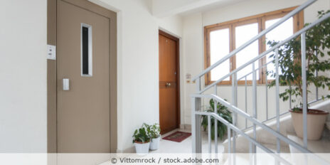 Hausflur eines Mehrfamilienhaus mit Blick auf die Treppe, eine Wohnungstür und die Fahrstuhltür.
