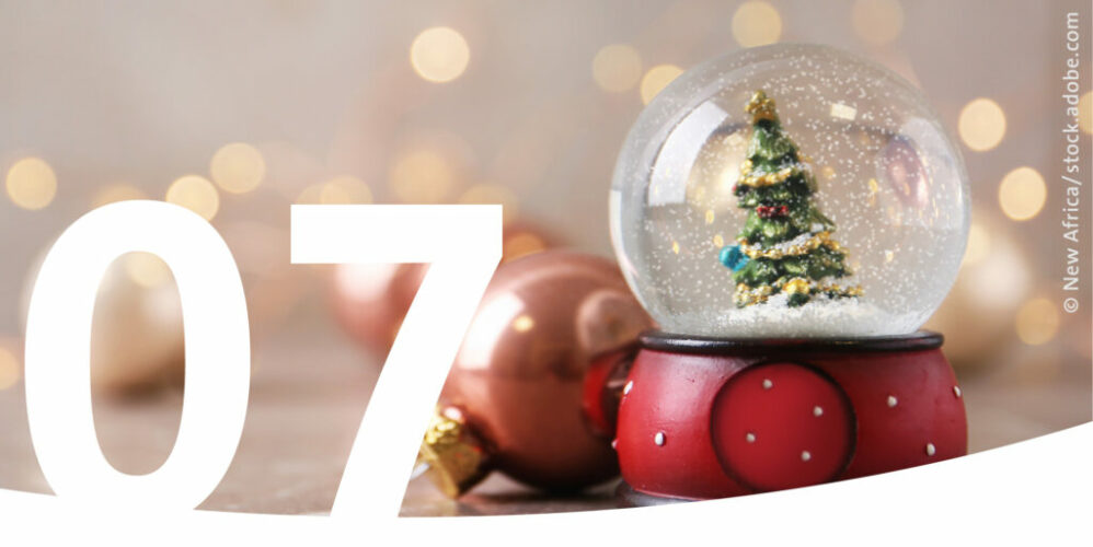 Schneekugel mit Weihnachtsbaum und im Vordergrund die Zahl 7.