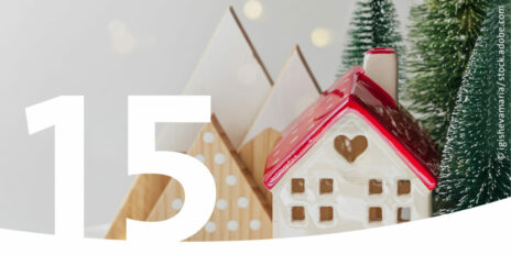 Kleines Weihnachtshaus mit Deko-Tannen und im Vordergrund die Zahl 15.