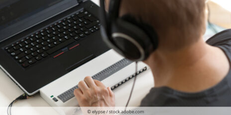 Blinde Person bei der Arbeit am Laptop mit Blindenschriftanzeige.