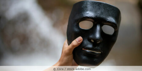 Männerhand hält eine schwarze Maske.