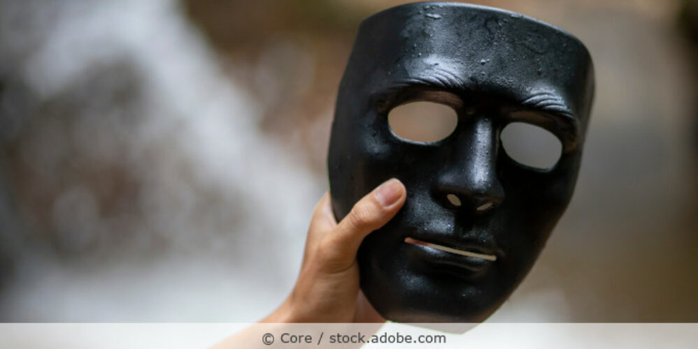 Männerhand hält eine schwarze Maske.