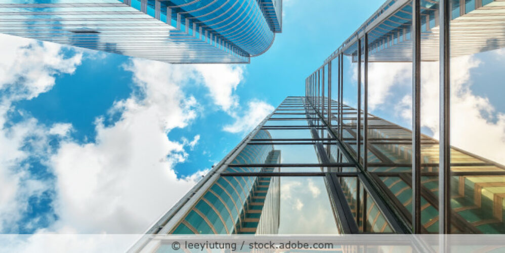 Die Glasfassade eines Hochhauses spiegelt sich in der Fassade des gegenüberliegenden Gebäudes.