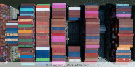Fahrendes Containerschiff beladen mit Containern in unterschiedlichen Farben von oben fotografiert.