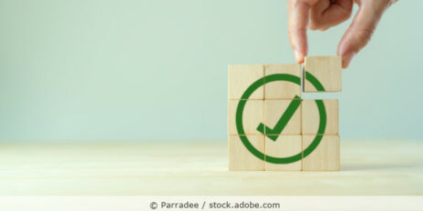 Quadrat aus Holzwürfeln auf denen ein Check-Haken abgebildet ist.